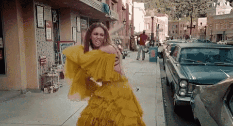 a woman in a yellow dress is standing on a street