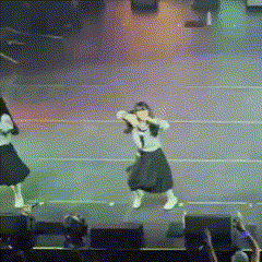 a girl in a black skirt is dancing on a stage in front of a crowd