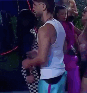 a man in a white tank top and blue shorts is standing next to a woman .