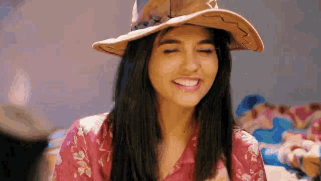 a woman wearing a cowboy hat and a pink shirt is smiling
