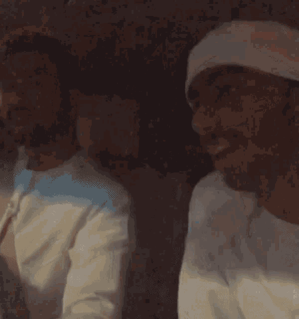 two men are sitting in a car and one of them is wearing a white turban .