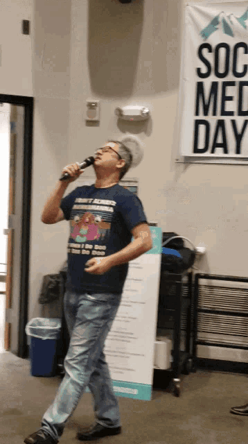 a man singing into a microphone in front of a banner that says social med day