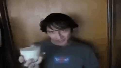 a man in a pepsi shirt is standing in front of a door and holding a remote control .