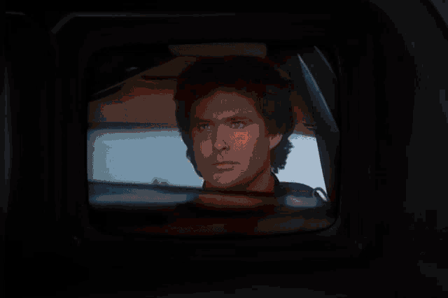 a black car is driving down a road in a purple light