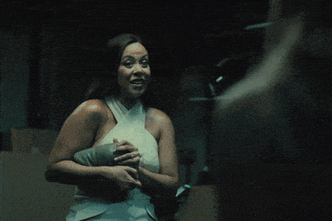 two women hugging each other in a dark room with one holding a knife
