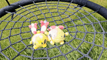 two stuffed animals are laying in a hammock