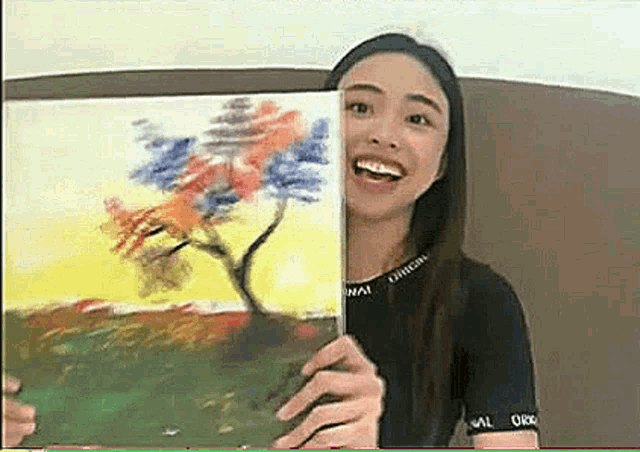 a woman is holding a painting of a tree behind her face