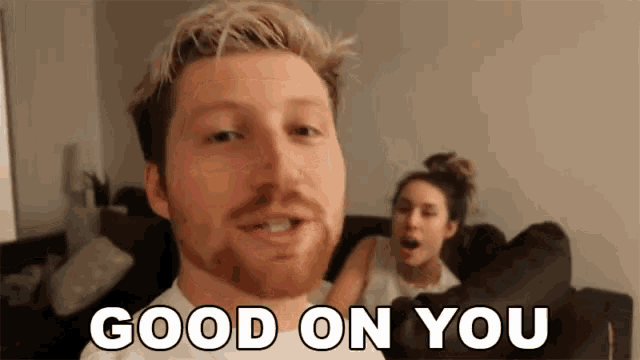 a man with a beard says good on you in front of a woman on a couch