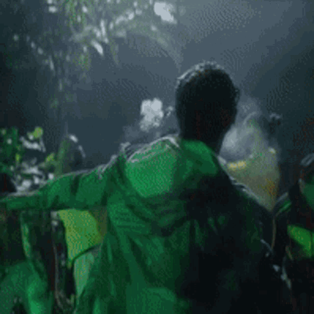 a man in a green jacket is dancing in a dark room