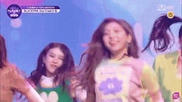 a group of girls are dancing on a stage and one of them is wearing a pink shirt .