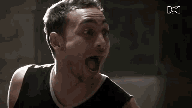 a man in a black tank top is screaming in front of a sign that says tci