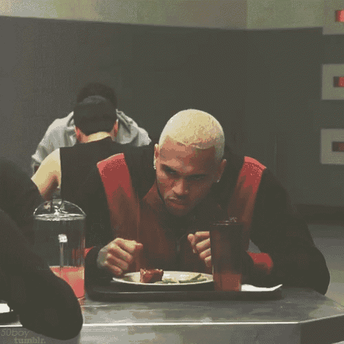 a man sitting at a table with a plate of food and a glass of water