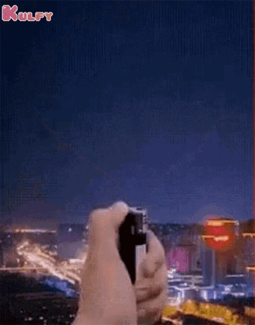 a person is holding a lighter in front of a city at night ..