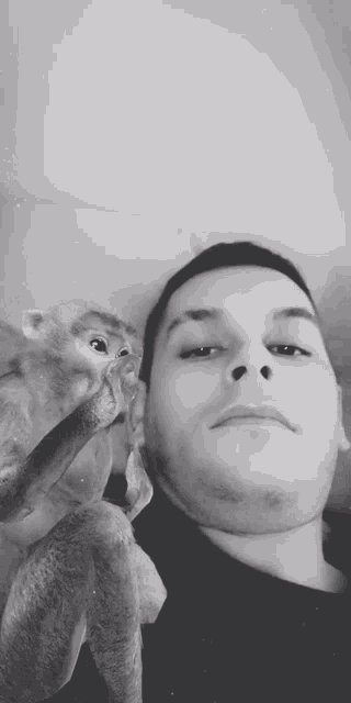 a black and white photo of a man holding a monkey on his shoulder .