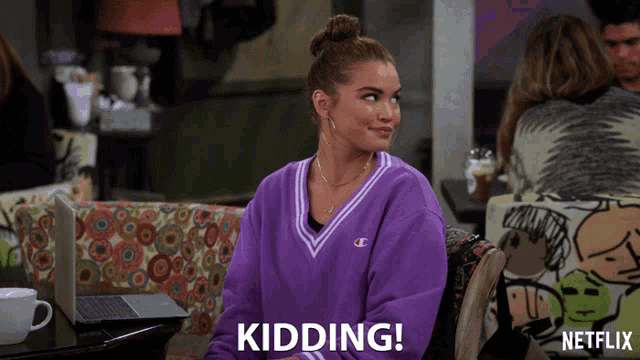 a woman in a purple sweater says kidding on the screen