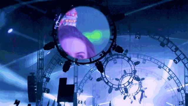 a woman 's face is projected on a large circle in the middle of a stage