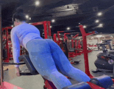 a woman in blue leggings is doing exercises in a gym