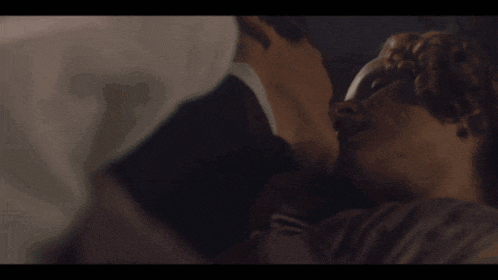 a close up of a man and woman kissing on a bed