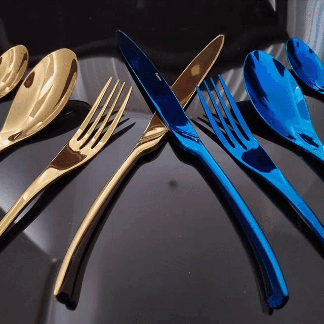 blue and gold silverware including a knife and fork on a black table