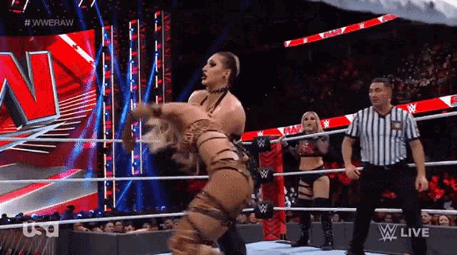 a female wrestler is being lifted in the air by a referee during a wrestling match