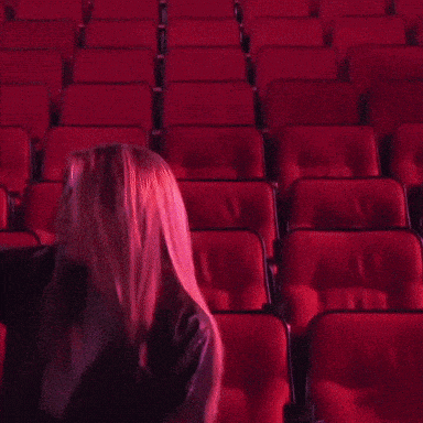 a woman in a purple sweatshirt is sitting in a theater