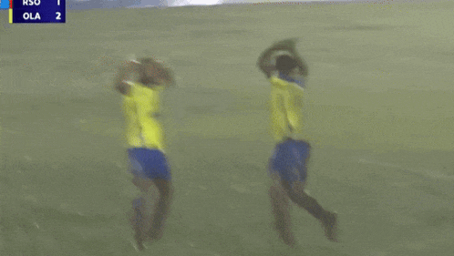 two soccer players on a field with a scoreboard in the background that says ola 2