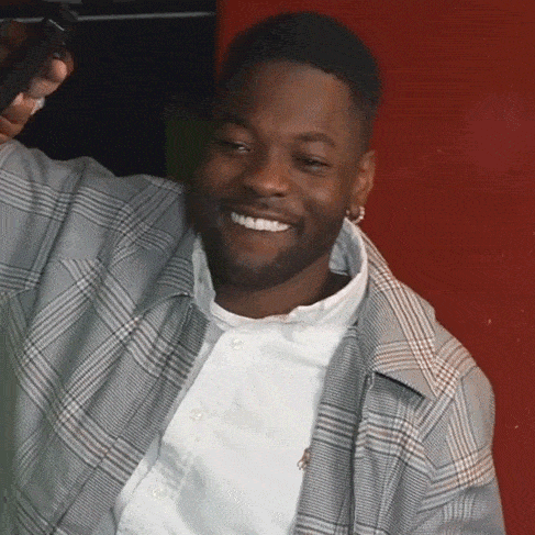 a man in a plaid shirt and white shirt smiles