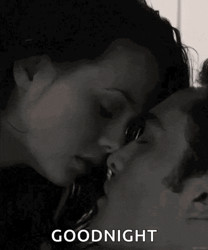 a man and a woman are kissing in bed and the man is kissing the woman on the forehead .
