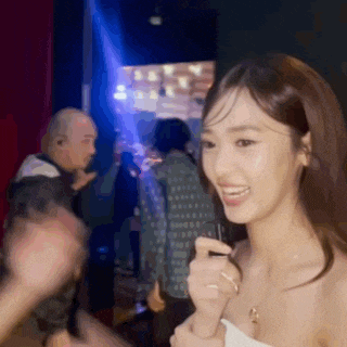 a woman is smiling while holding a microphone in a crowd of people .