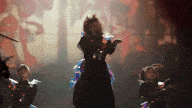 a woman in a black dress is dancing on a stage in front of a painting