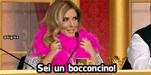 a woman wearing a pink boa is sitting in front of a microphone and says sei un bocconcino !