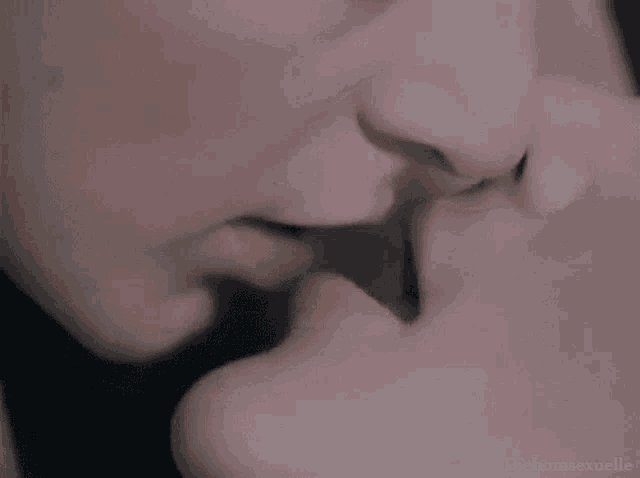 a man and a woman are kissing each other in a close up of their lips .