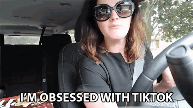 a woman driving a car with the words i 'm obsessed with tiktok