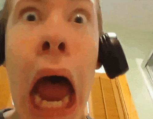 a close up of a person 's face with headphones on making a funny face .
