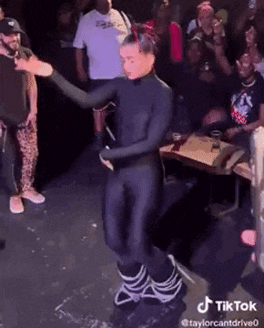 a woman in a black bodysuit is dancing on stage in front of a crowd .