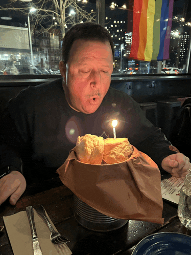 a man blows out a candle on top of a bowl of food