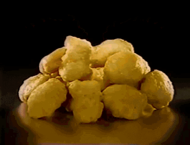 a pile of popcorn is sitting on a table with a black background