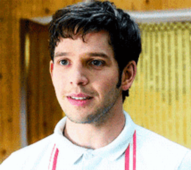 a man wearing a white shirt and a red apron is smiling