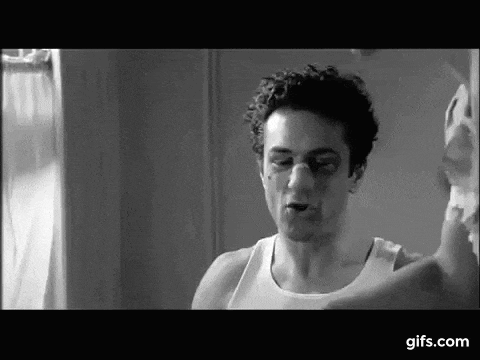 a man in a white tank top is standing in front of a mirror .