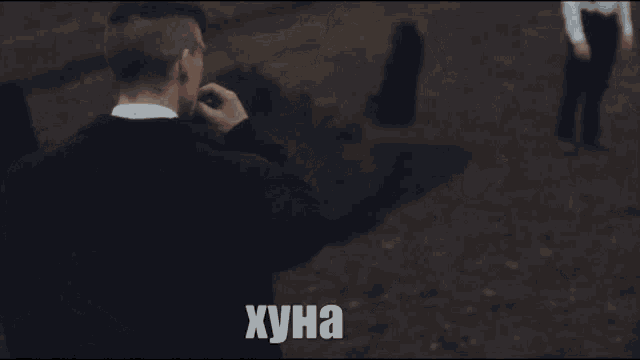 a man in a suit is smoking a cigarette with the word хуна written on the bottom