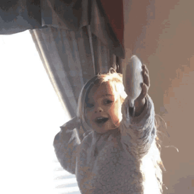a little girl in a sweater is holding a white object in her hands