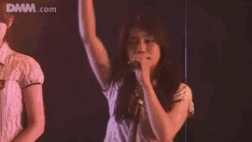a woman is clapping in front of a dmm.com logo