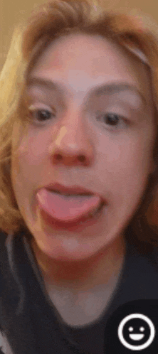 a young woman is sticking her tongue out in front of a smiley face .