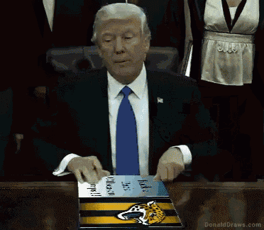 a man in a suit and tie is sitting at a table holding a book with a jaguars logo