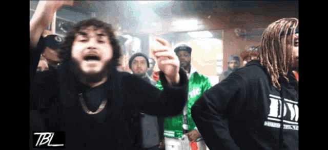 a group of men are dancing in a room with the letters tbl on the bottom right