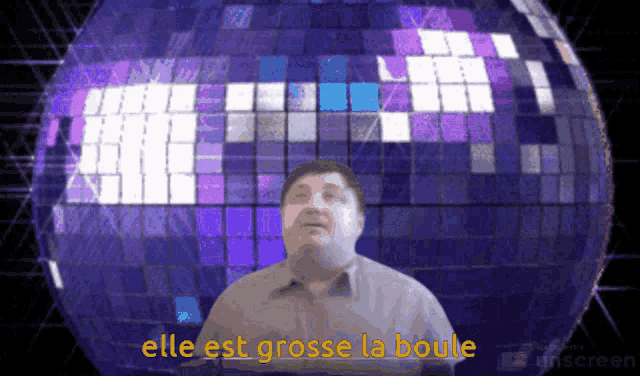a man is standing in front of a disco ball with the words elle est grosse la boule written in yellow