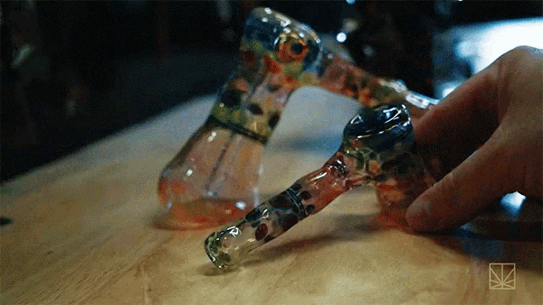 a person is holding a glass pipe with a marijuana logo on the bottom