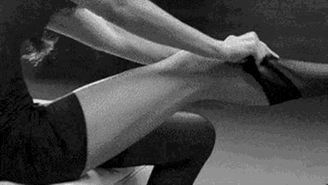 a black and white photo of a woman 's legs being stretched .