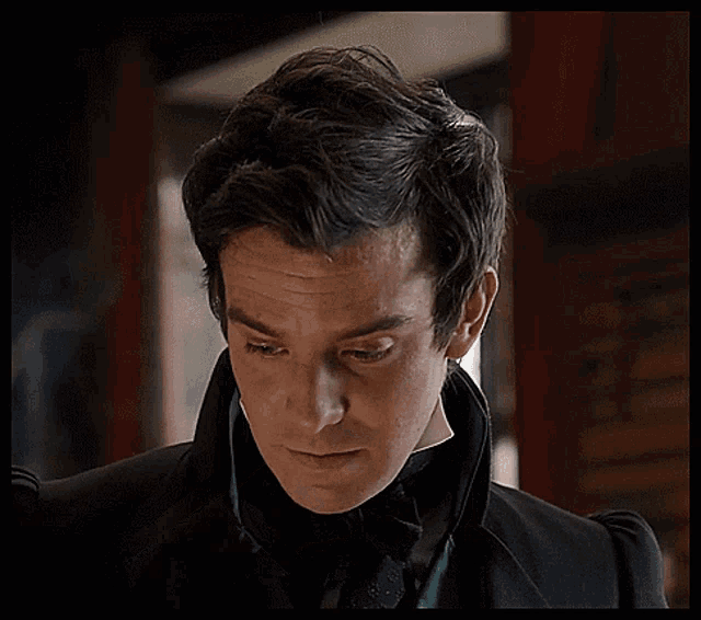 a man in a suit and tie is adjusting his collar