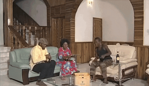 a man sits on a couch next to a woman and a man sitting on a table
